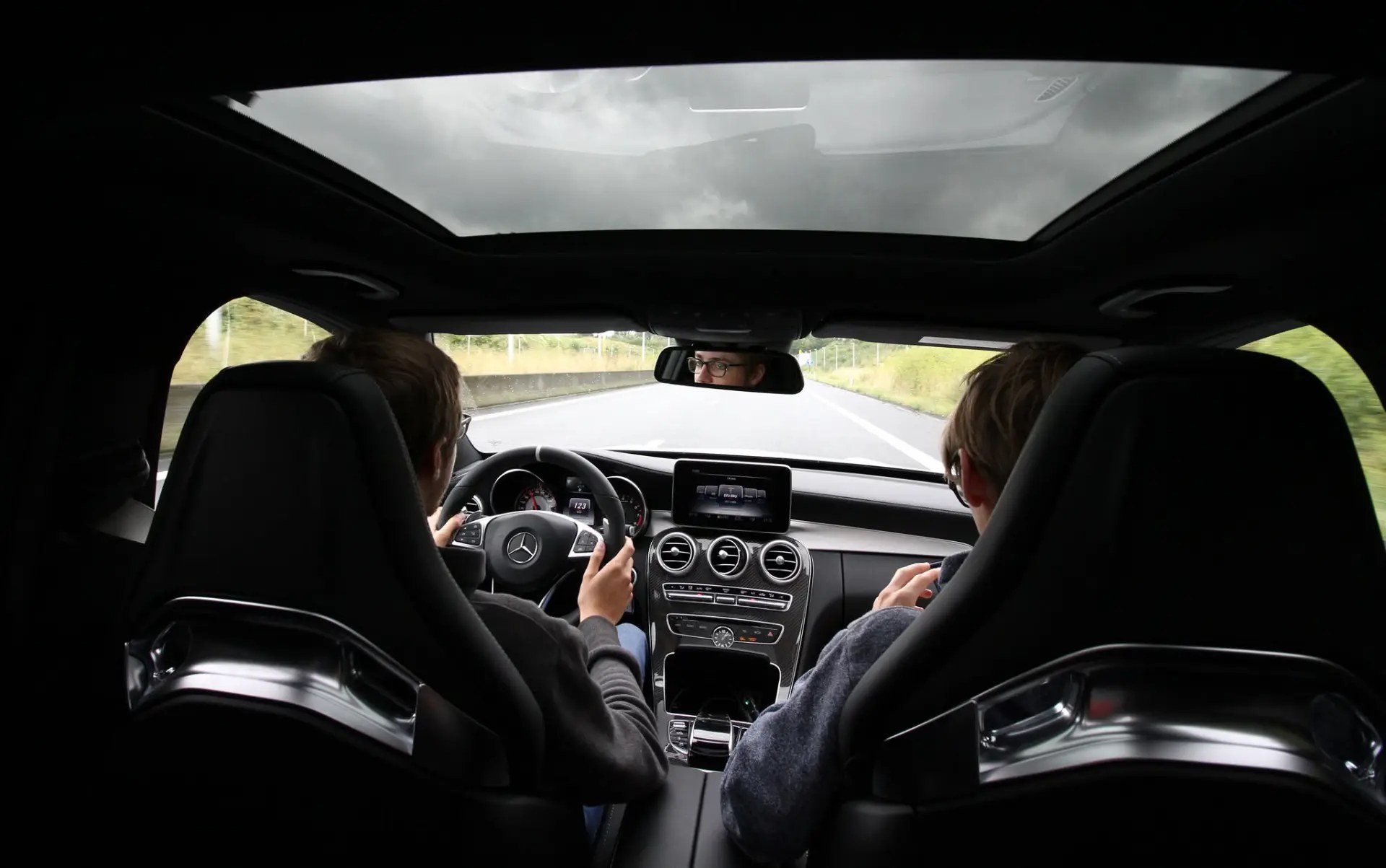Two passengers in the back seat looking out through a panoramic roof
