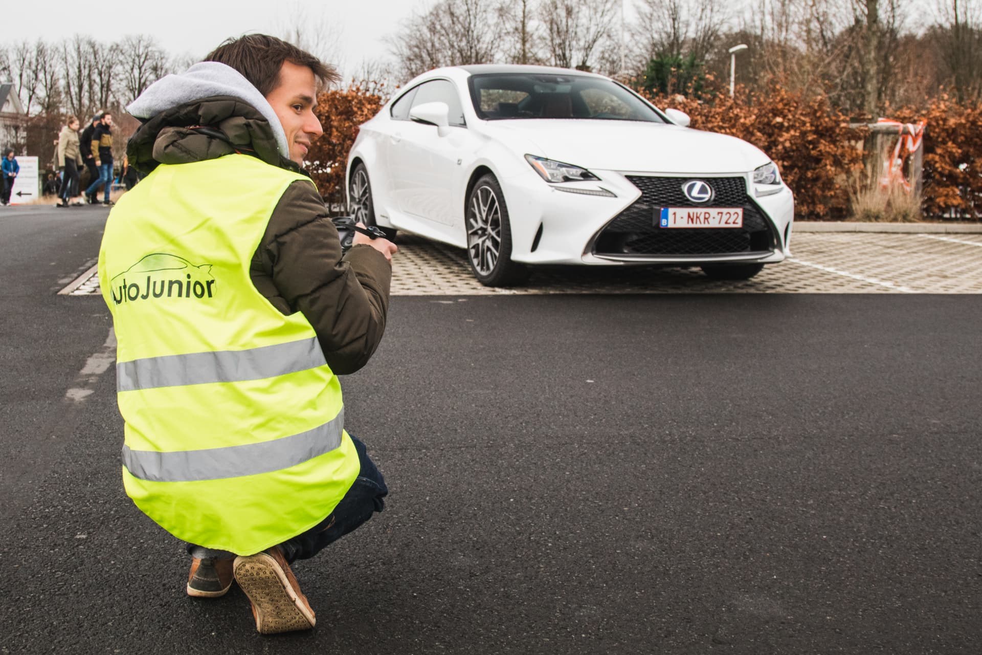 Photographer in an AutoJunior vest filming a white coupé