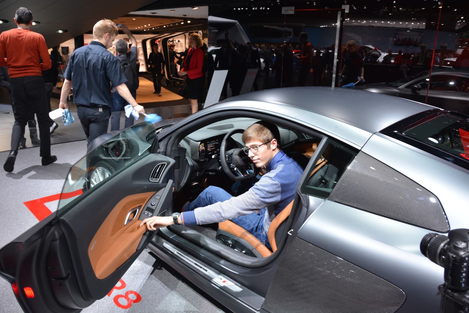 Louis seated in a silver sports car at a motor show