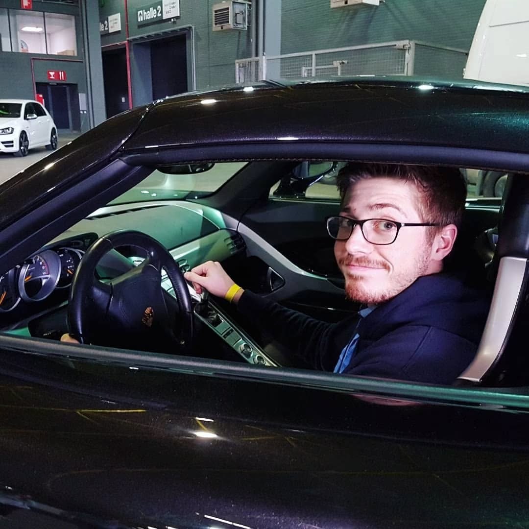 Louis smiling from the driver's seat of a dark sports car